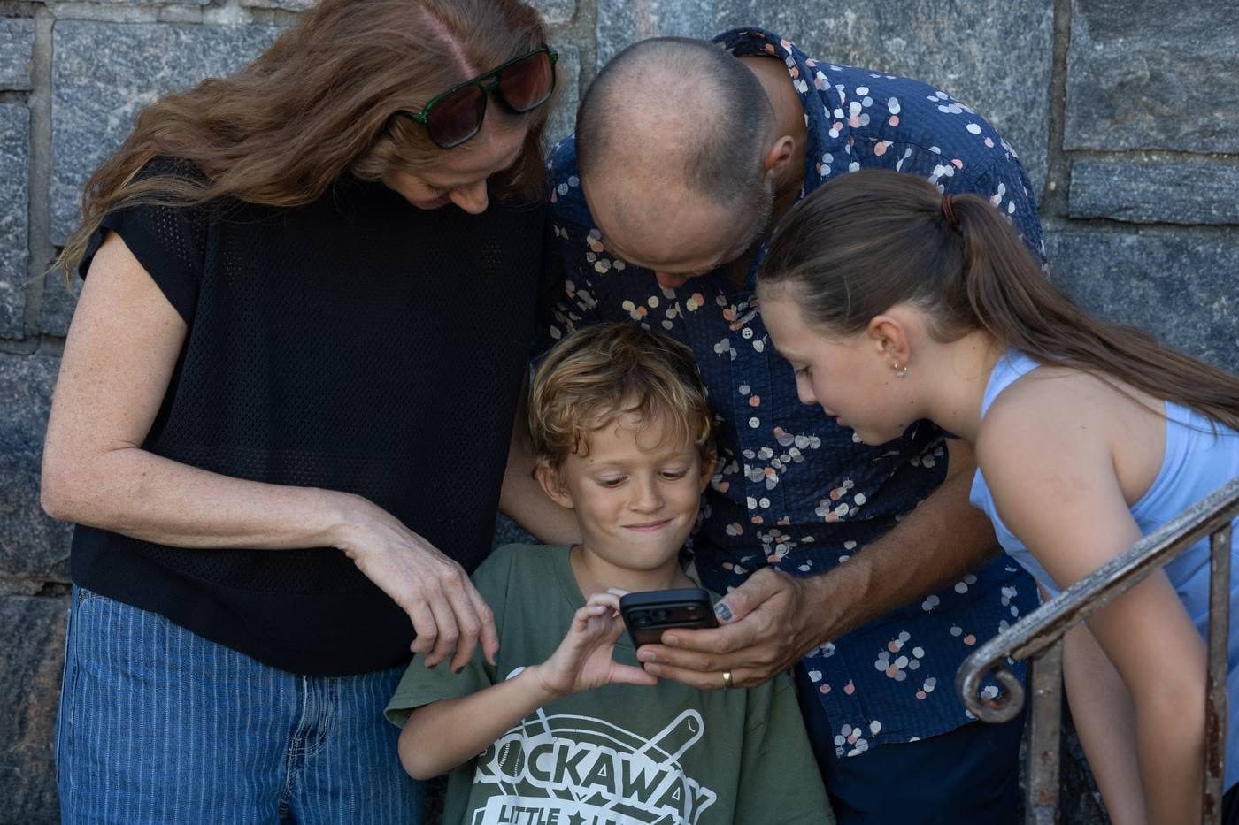 A Rockaway family looking at a phone together, son in a Rockaway Little League shirt